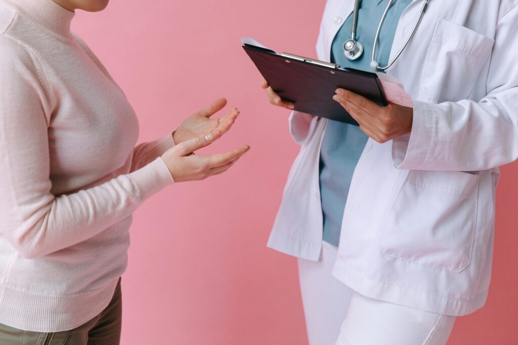 pexels-photo-7659869-7659869-1 Close-up of a patient consulting a doctor with a clipboard in a medical setting.